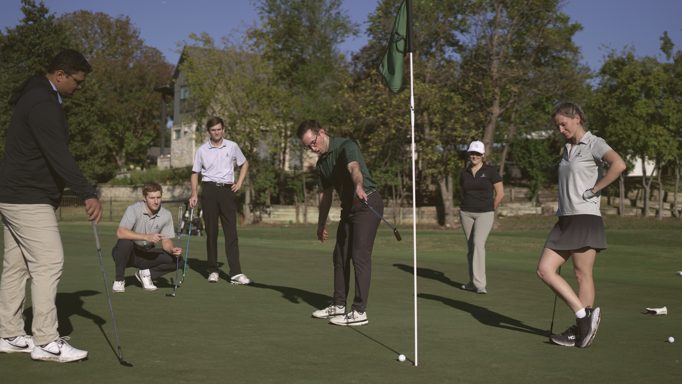 Golfers trying clubs together on the putting green